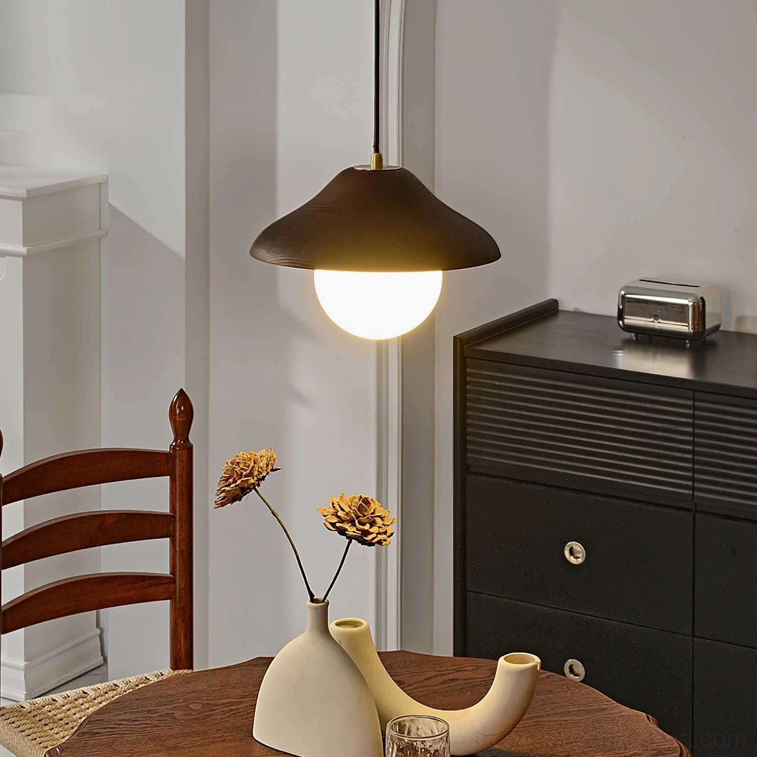 Delano wood and glass pendant displayed on sideboard table corner, showcasing design detail and warm light output
