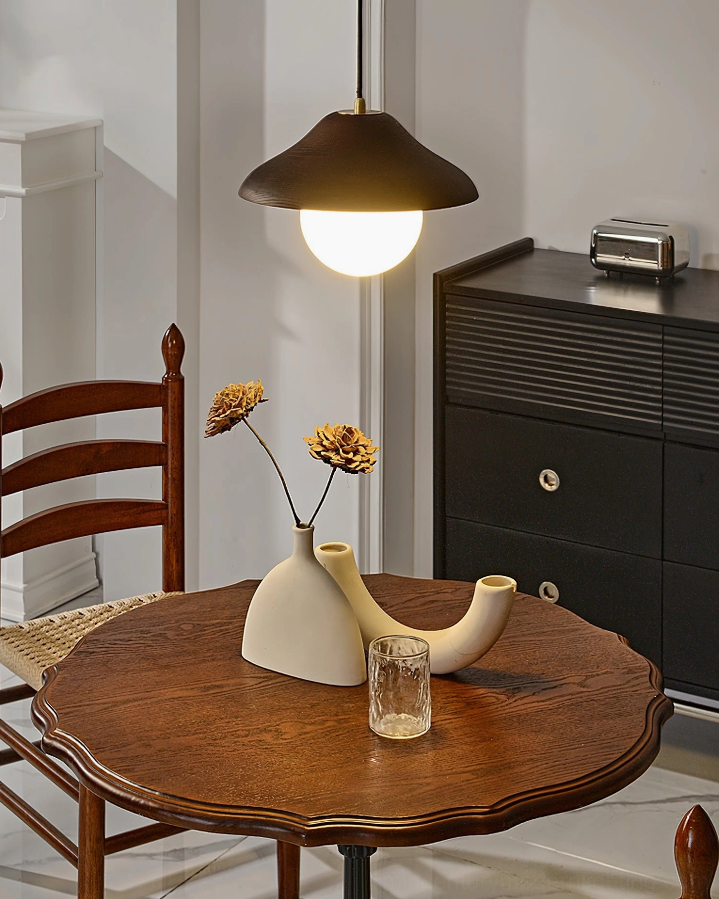 Delano pendant with brass finish coupling suspended above small wooden dining table area, side angle view