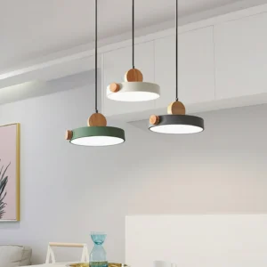 Three-pack Detroit pendant lights in mixed finishes suspended above modern dining room table with wood top