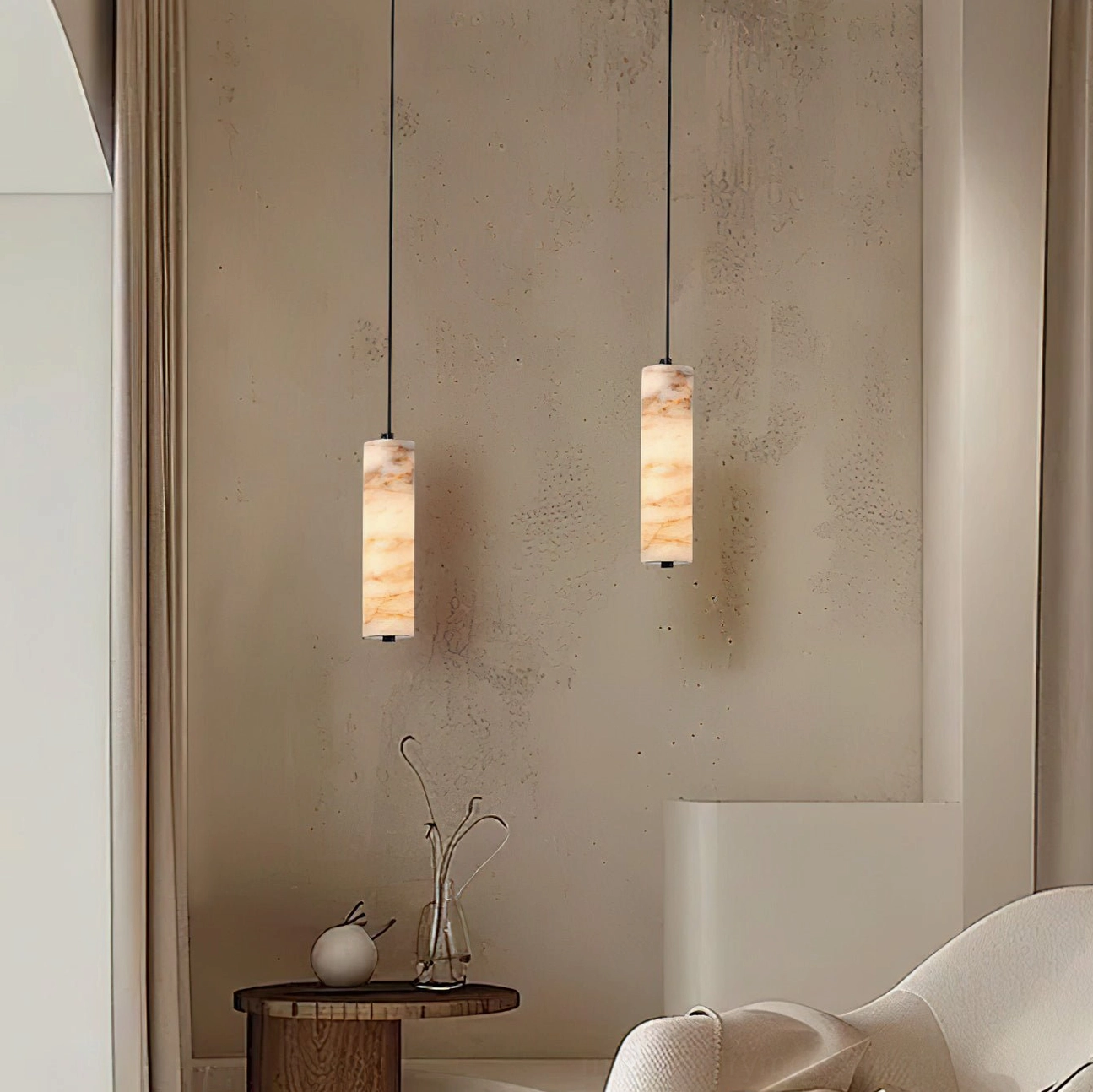 Twin Devane alabaster pendant lights in minimalist living room with accent wall and modern furnishings, creating paired sculptural lighting arrangement