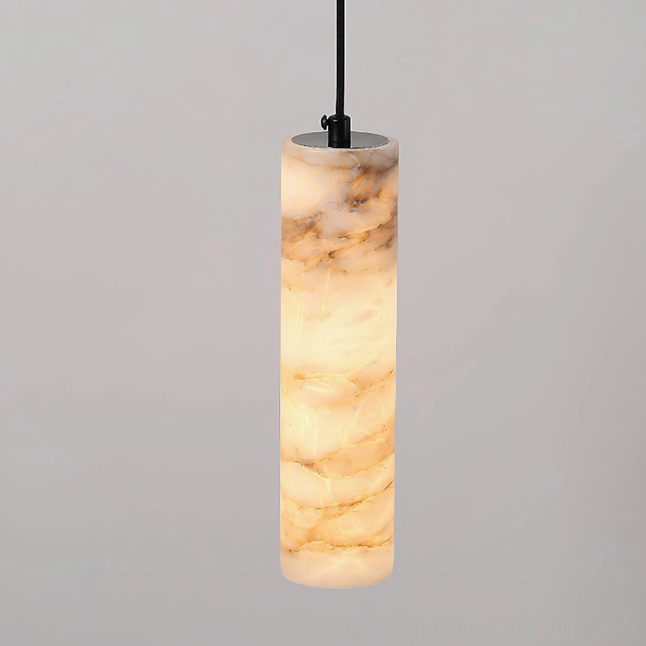 Illuminated Devane alabaster pendant light showing thick cylindrical shade, warm glow through translucent stone, and natural geological veining patterns