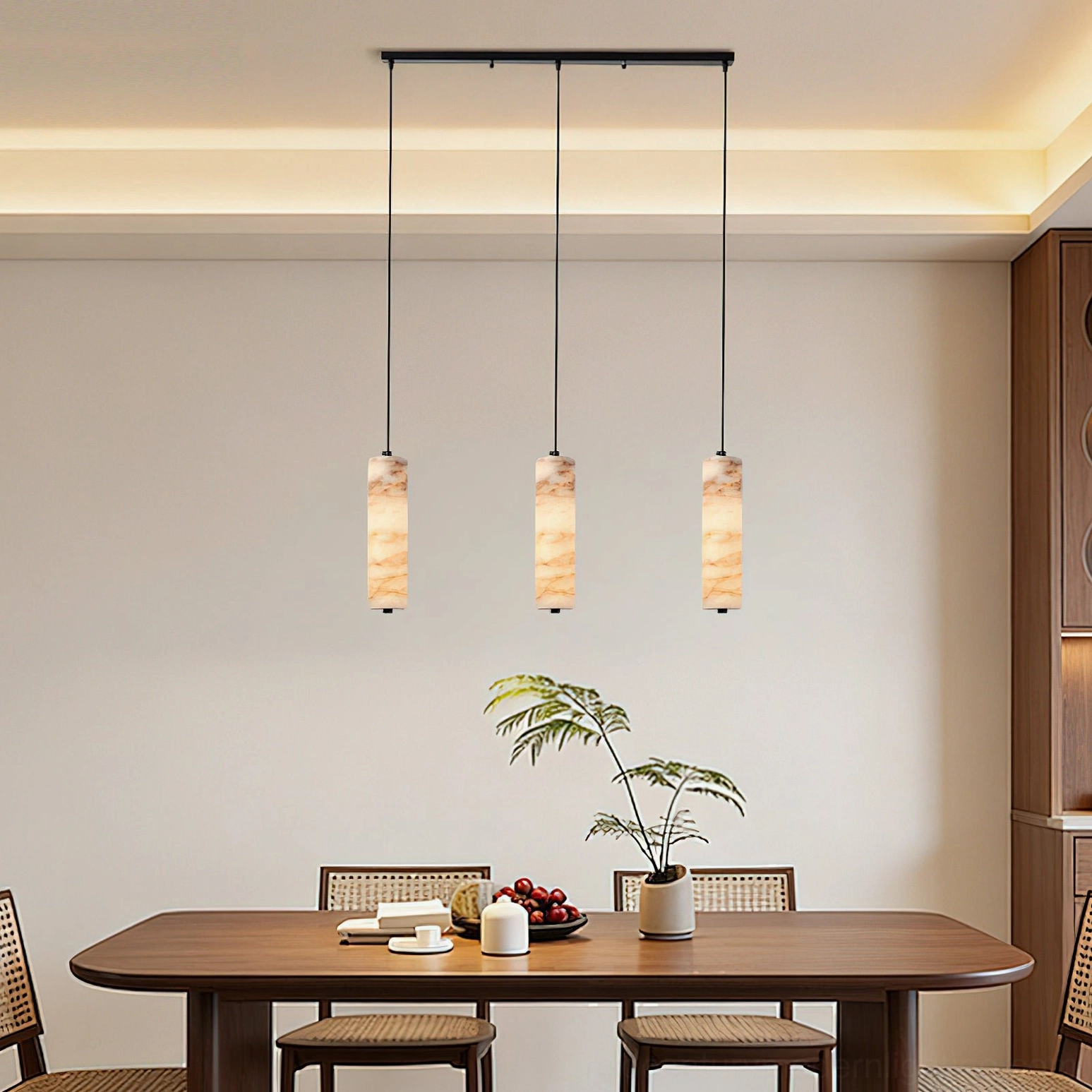 Triple Devane alabaster pendant lights suspended in dining room above wooden table with chairs and potted plants, creating dramatic linear lighting installation