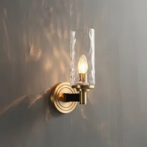 Devora compact wall lamp close-up showing warm brass finish and candle-style bulb detail