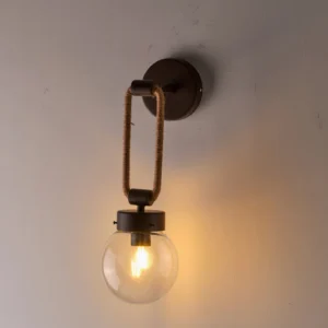 Dillon wall lamp illuminated indoors casting warm ambient glow on light gray wall demonstrating atmospheric lighting effect