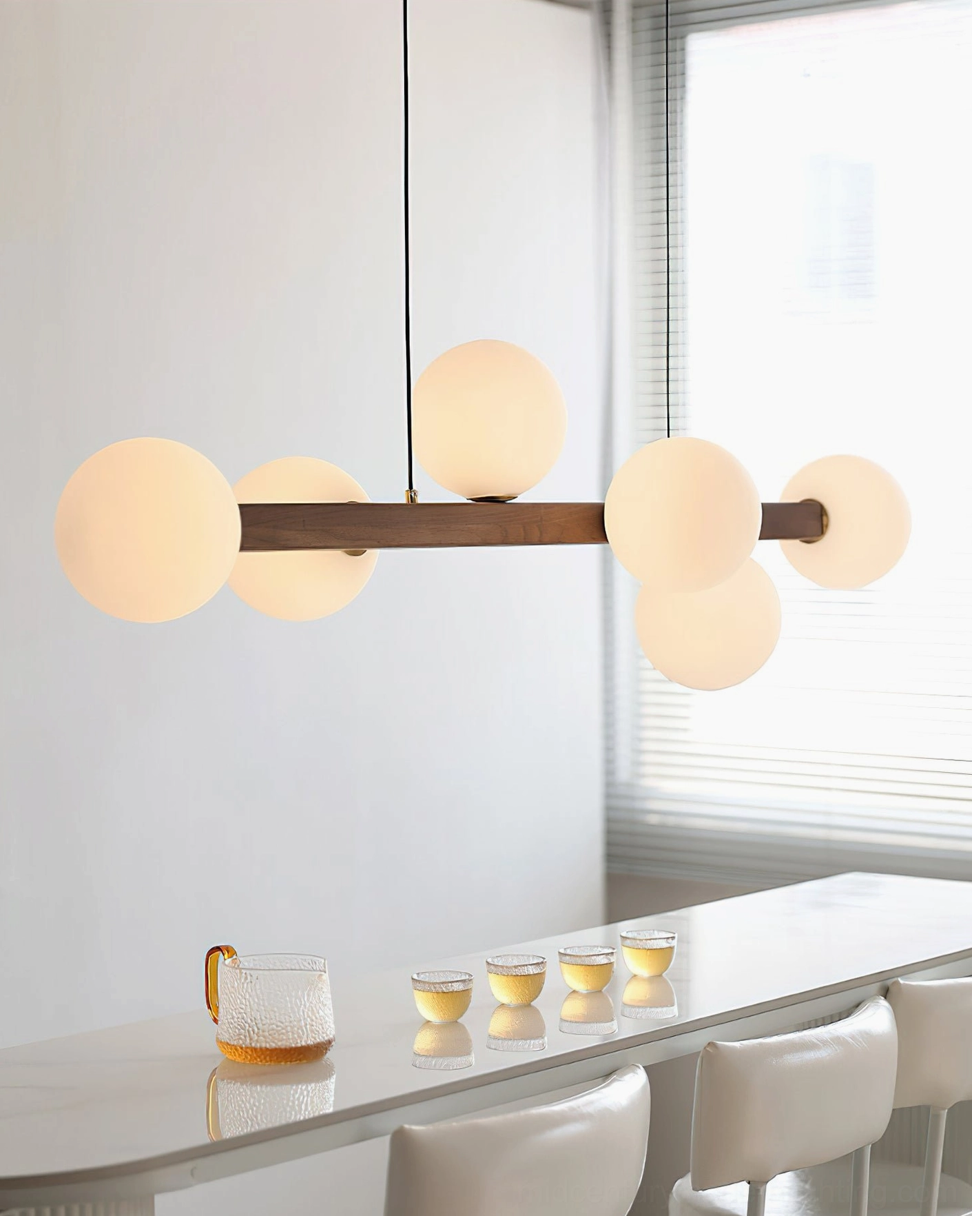 Dioniso linear chandelier side view in bright dining space with warm light glowing