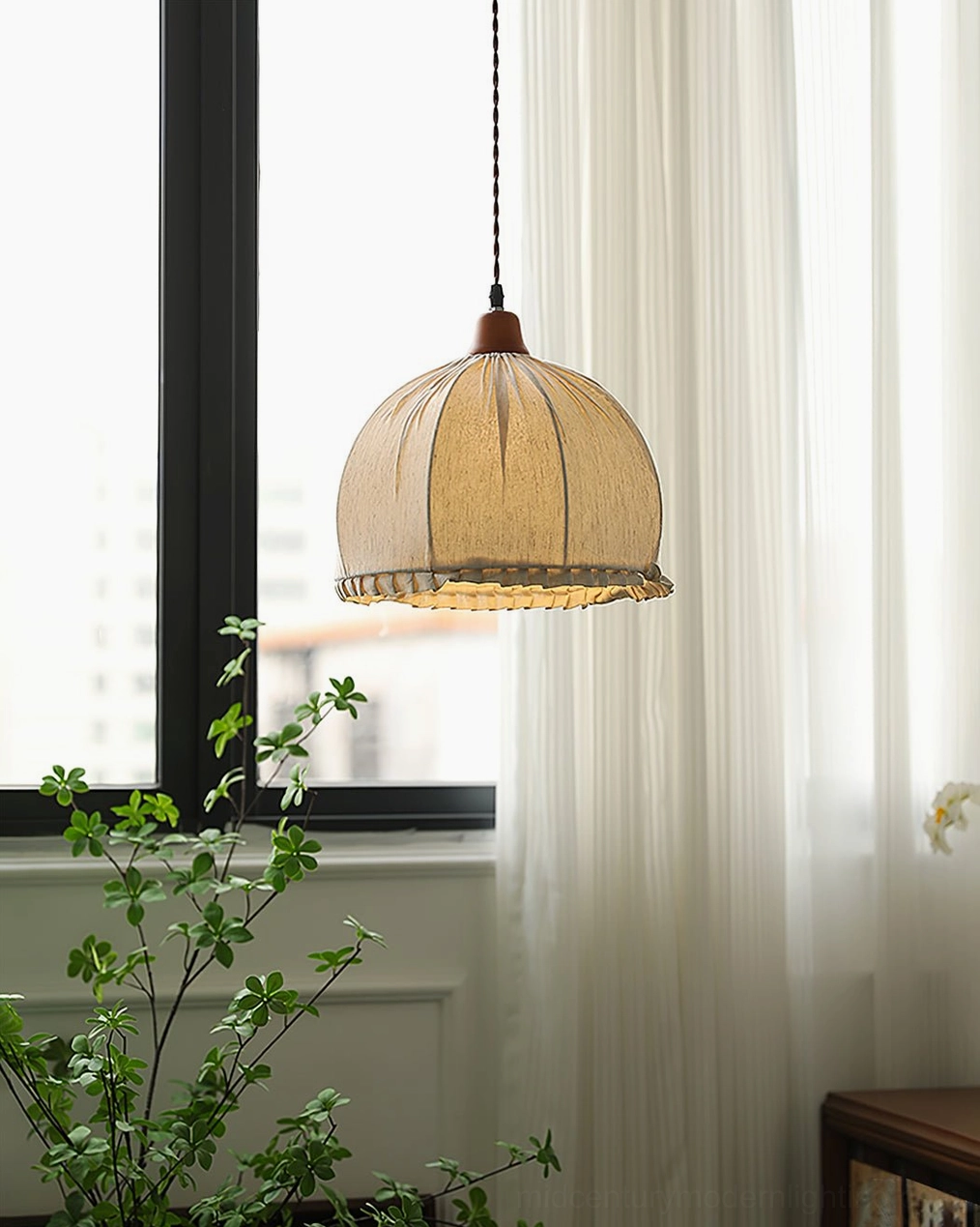 Dippa pendant light side view showing ruffled fabric hem and warm ambient glow in residential living space