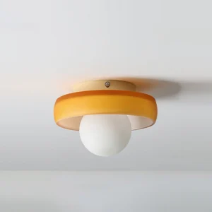 Mid-century modern orange disc ceiling light fixture mounted flush to ceiling, flat overhead view