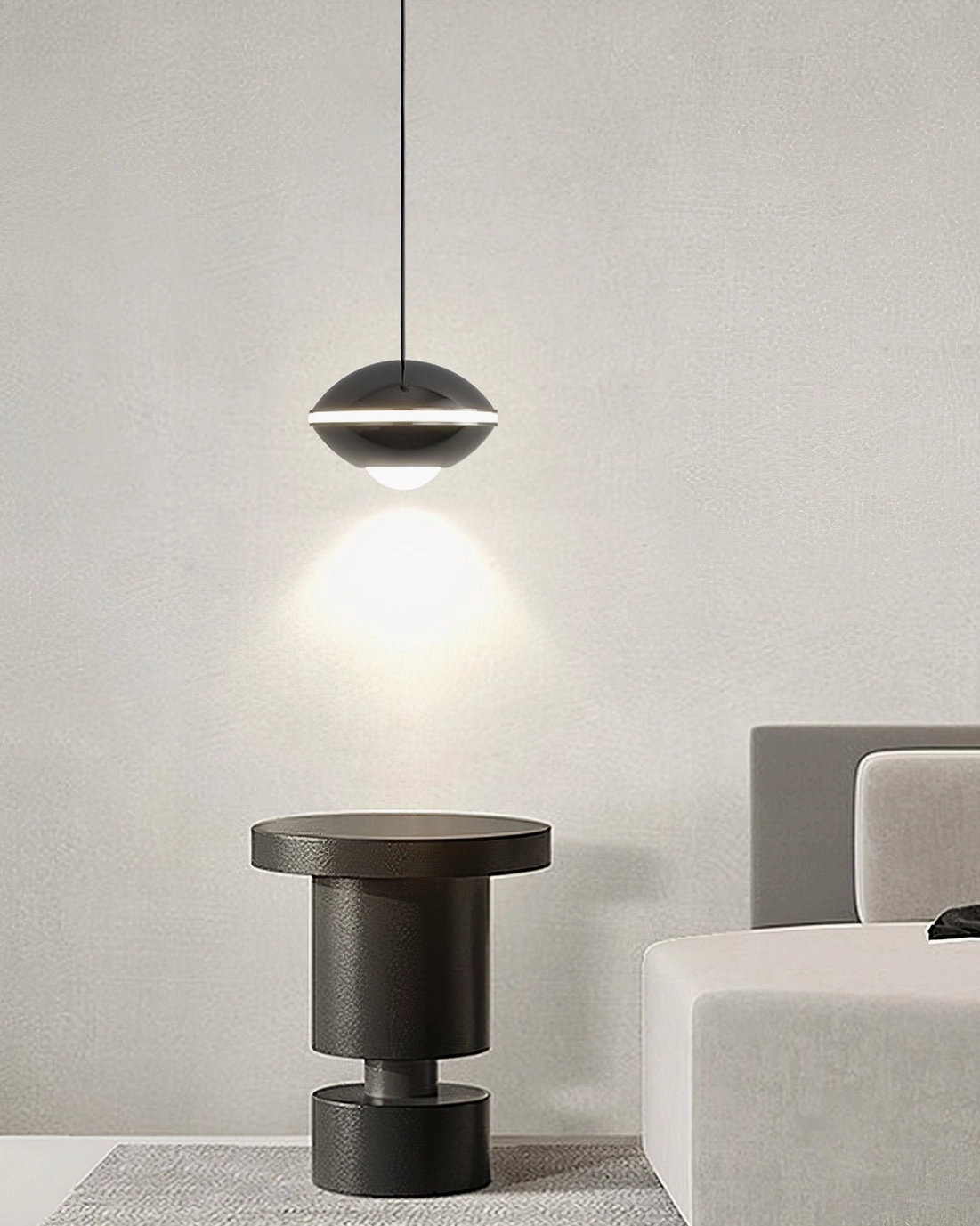 Contemporary disc pendant light in minimalist living nook, dark rounded metal shade with warm glow
