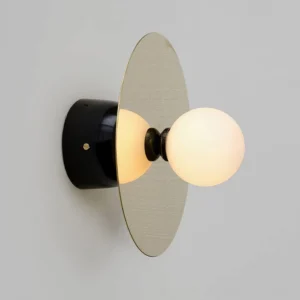 Side profile view of geometric brass disc wall light with frosted glass sphere detail