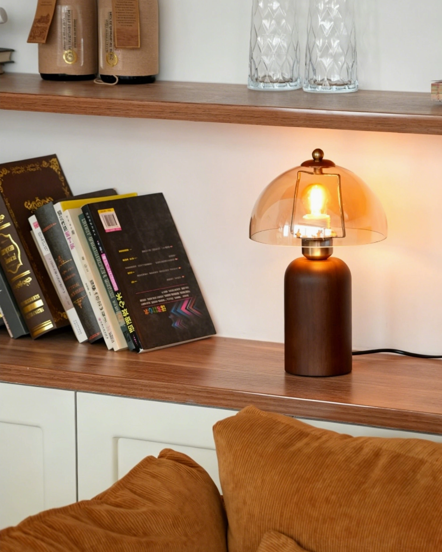 Disko table lamp with amber glass dome on display shelf, surrounded by books and decorative glassware