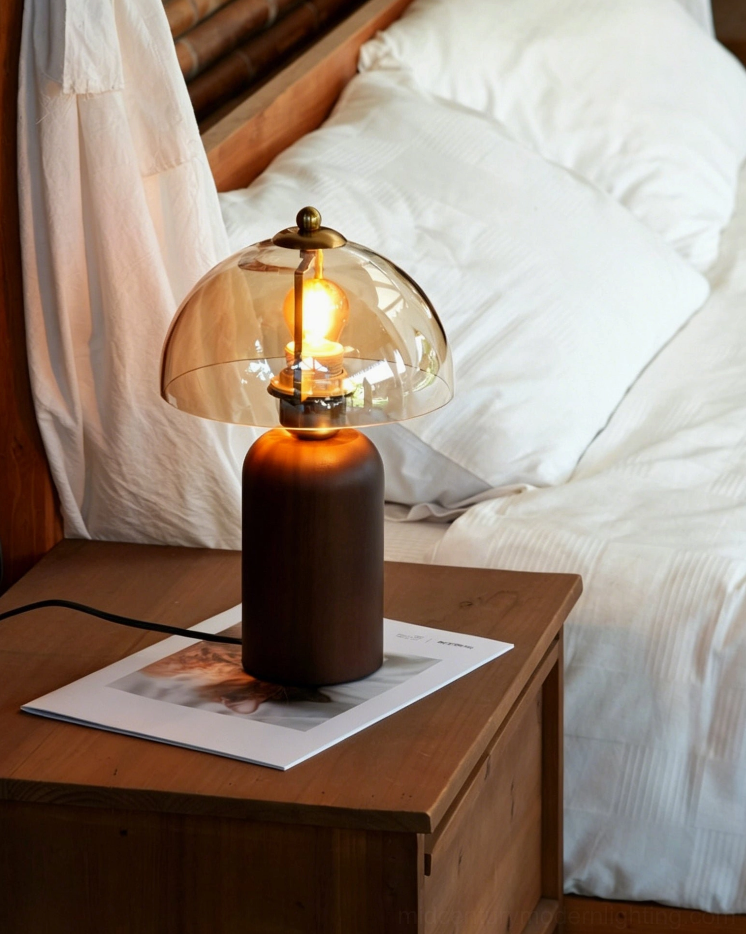 Disko mid-century modern lamp on bedroom nightstand, soft amber glow beside white linen bedding