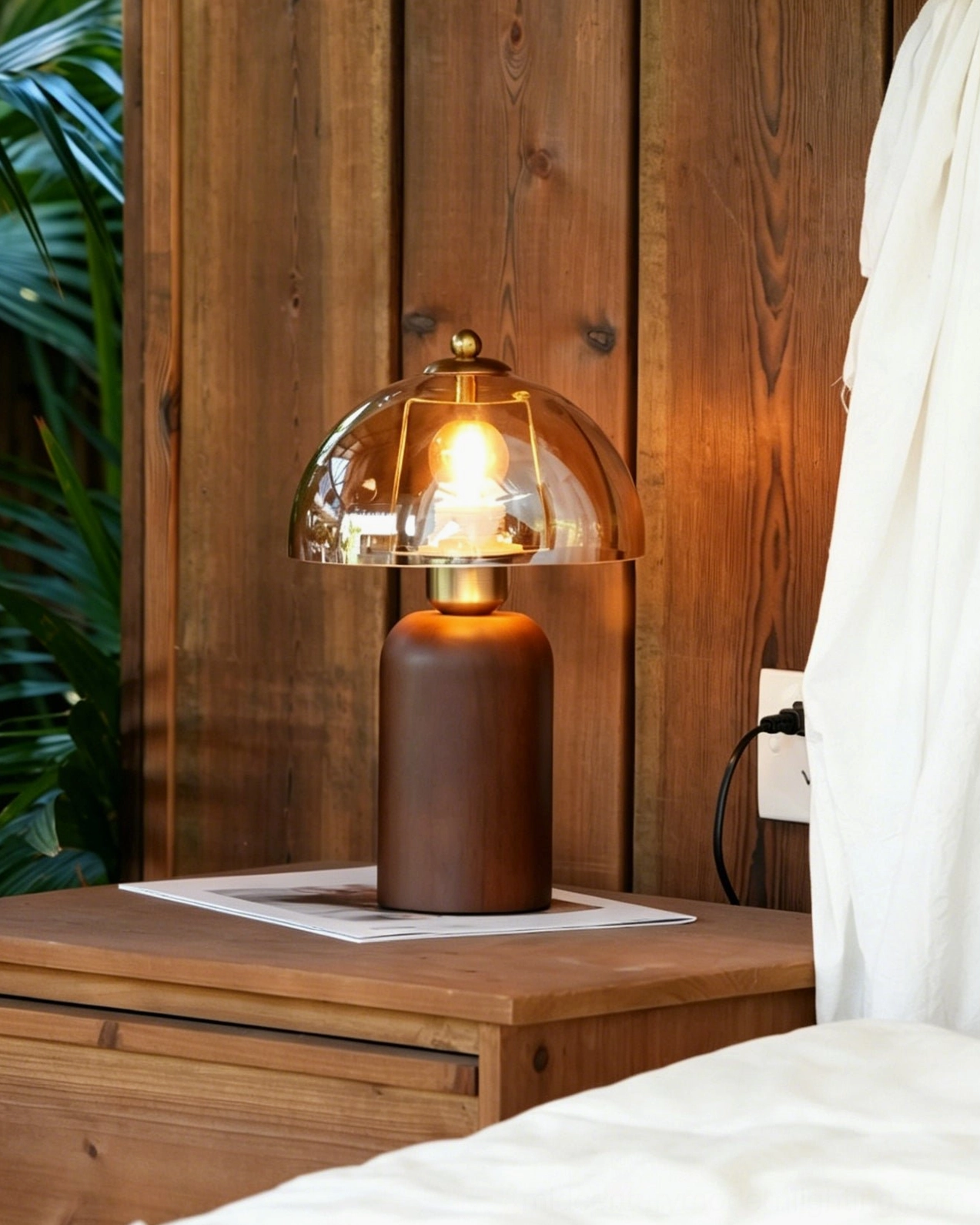 Disko table lamp positioned on wooden bedside table, warm amber glass shade with wood panel wall background