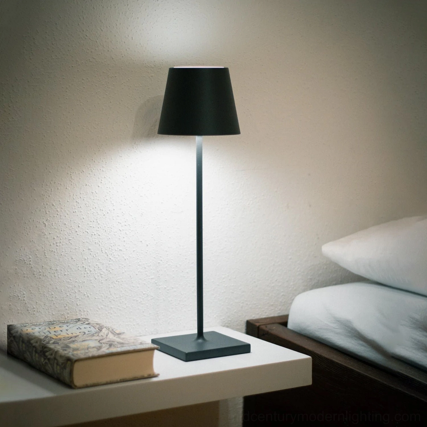 Black matte Doku cordless table lamp on bedroom nightstand, warm glow lighting beside bed