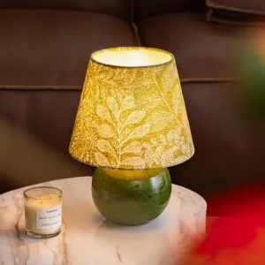 Dolly table lamp styled in modern living room with brown leather sofa, marble side table, and warm botanical glow