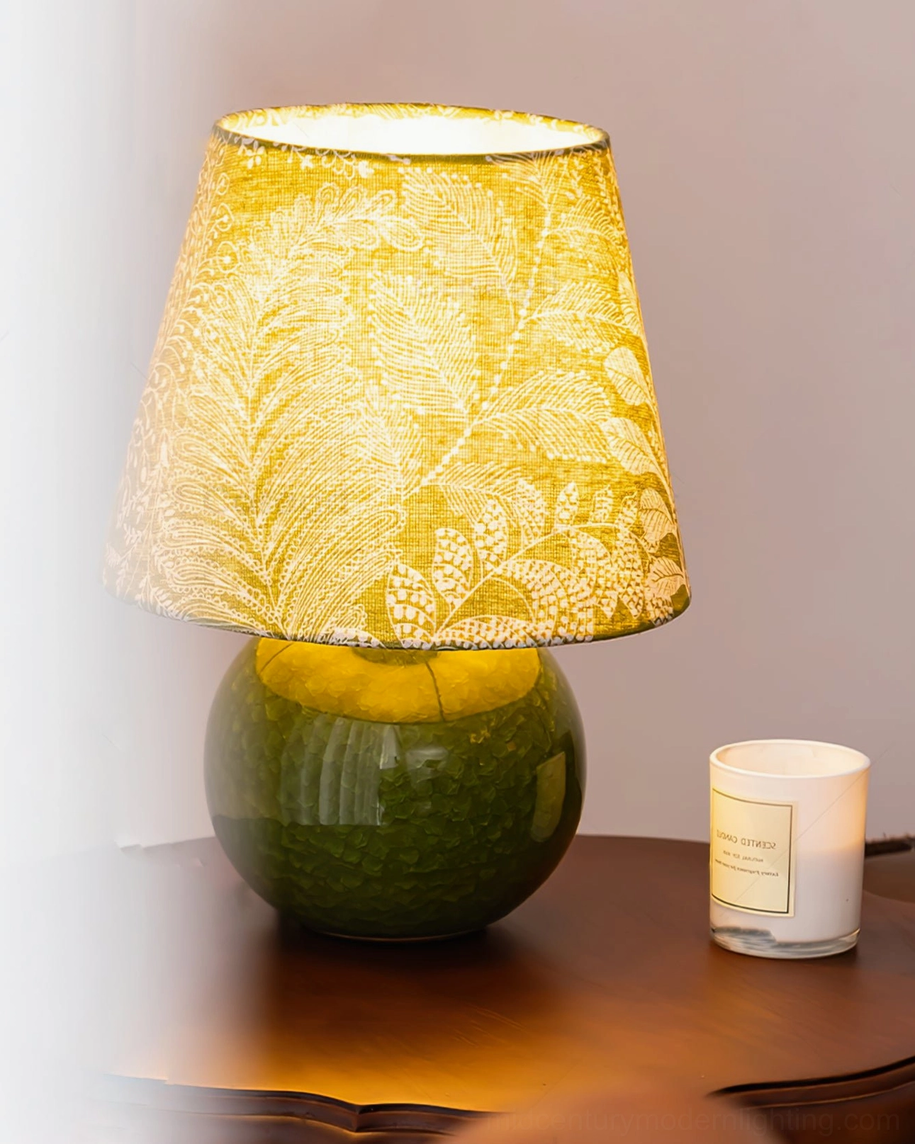 Dolly table lamp glowing with warm yellow light on wooden side table, paired with scented candle