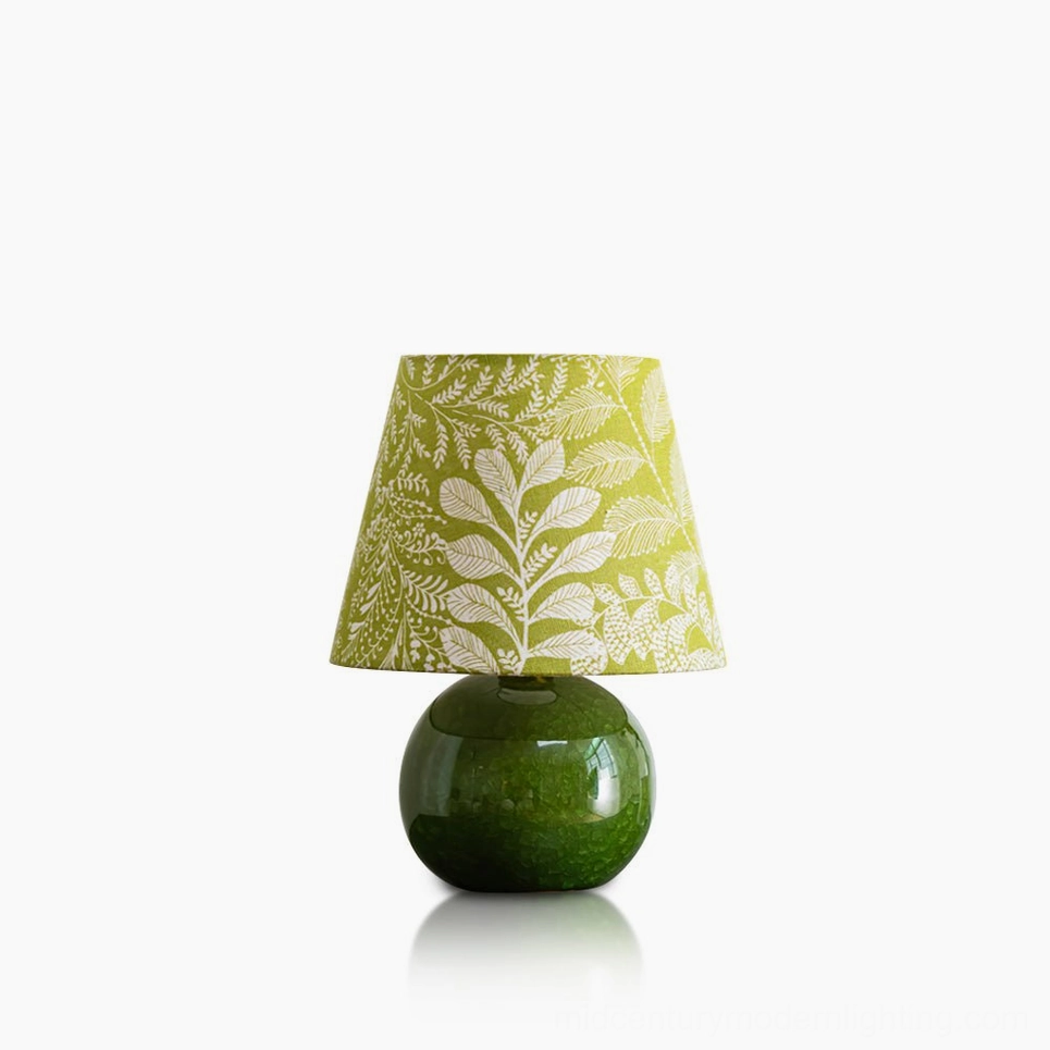 Dolly ceramic table lamp with olive green spherical base and botanical leaf print shade, front studio view