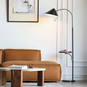 Arc floor lamp with side tray in modern living room setting beside tan leather sofa, mid-century minimalist style