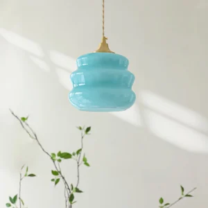 Donna mid-century pendant lamp side angle view with glossy aqua glass shade casting shadows from natural light with green foliage