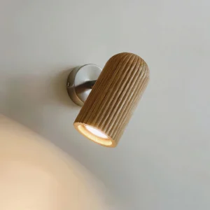 Close-up detail of Donovan wall lamp showing warm light diffusion through ribbed wood texture and metal fixture