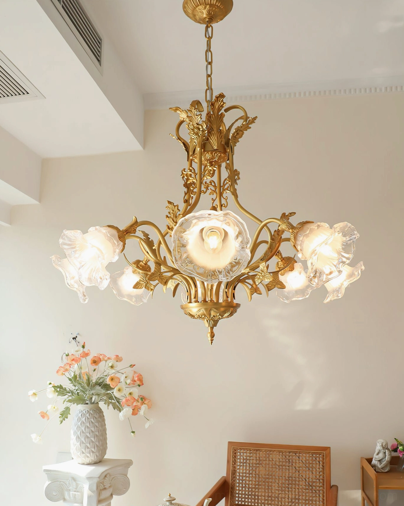 Multi-arm brass flower chandelier illuminating dining area with rattan chairs and botanical decor