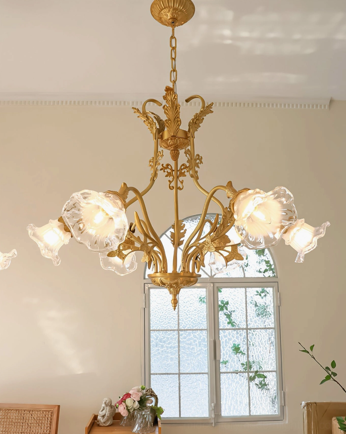 Ornate brass flower chandelier with carved frame and flower-shaped glass shades in elegant interior space