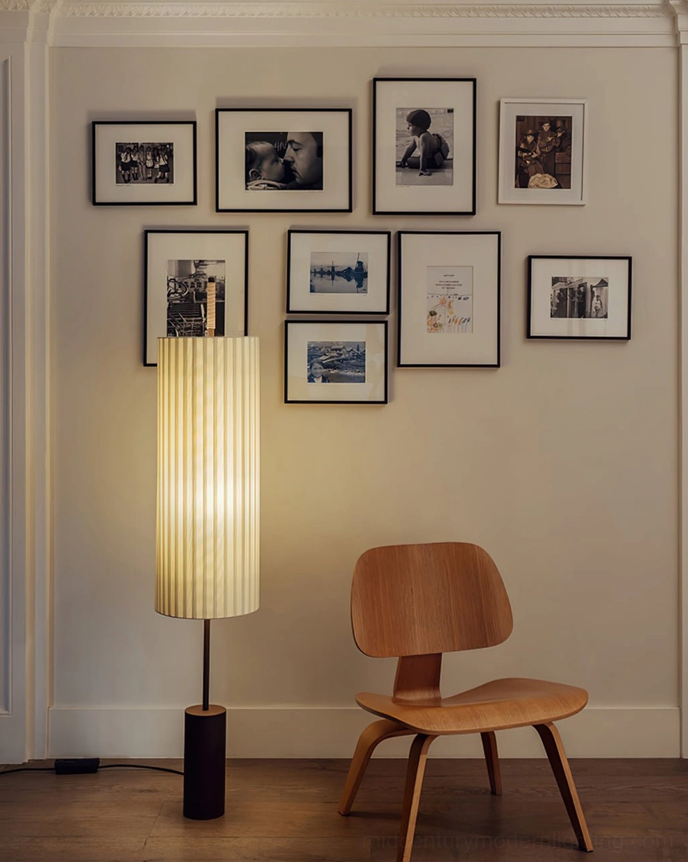Dorica sculptural floor lamp glowing in modern living room with gallery wall and wooden chair