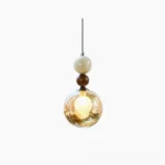 Dot pendant light with cognac amber glass sphere and walnut wood bead accents on white studio background, front overhead view