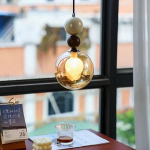 Mid-century modern pendant light hanging above desk with warm Edison bulb glow, stacked wood bead details visible