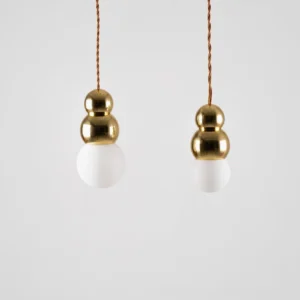 Twin ball pendant lights with matching gold fixtures and frosted white bulbs, stacked configuration studio shot