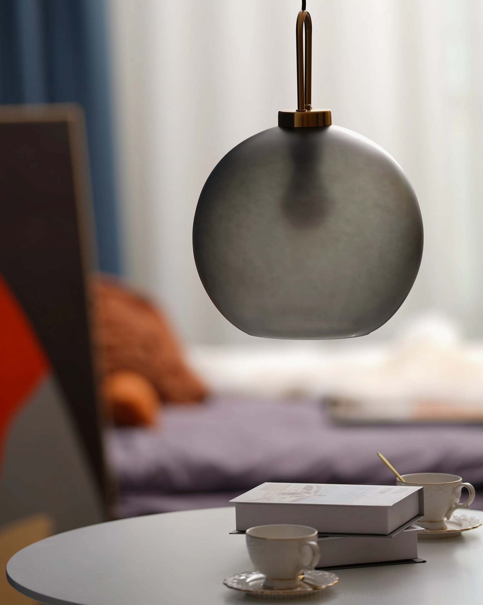 Two matching matte dark gray spherical smoked glass pendants in close-up angled view over dining area