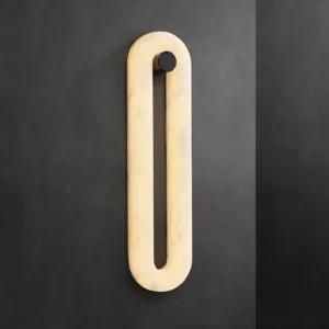 Dromo modern wall sconce glowing with warm LED light against dark gray wall, sculptural alabaster fixture