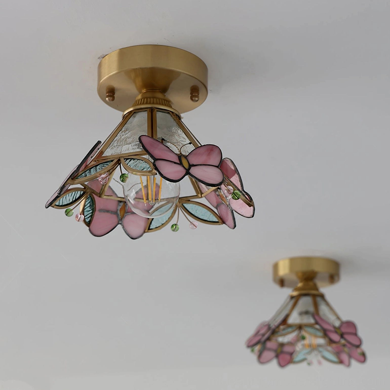 Two matching butterfly stained glass ceiling lamps in different sizes mounted on white wall, side-by-side comparison