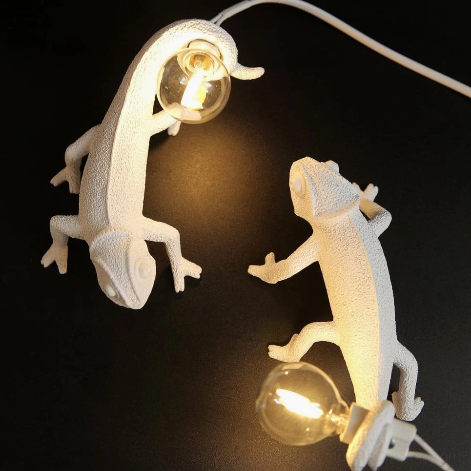 Dual chameleon wall sconces in different climbing poses on black background, modern sculptural lighting pair