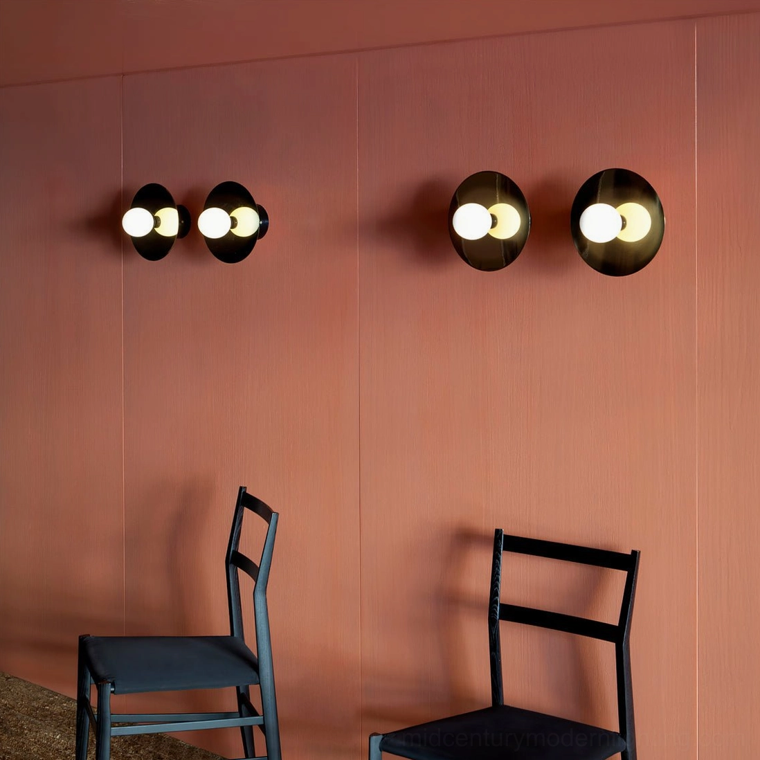 Double-head black disc sphere wall sconces with frosted glass bulbs on terracotta accent wall