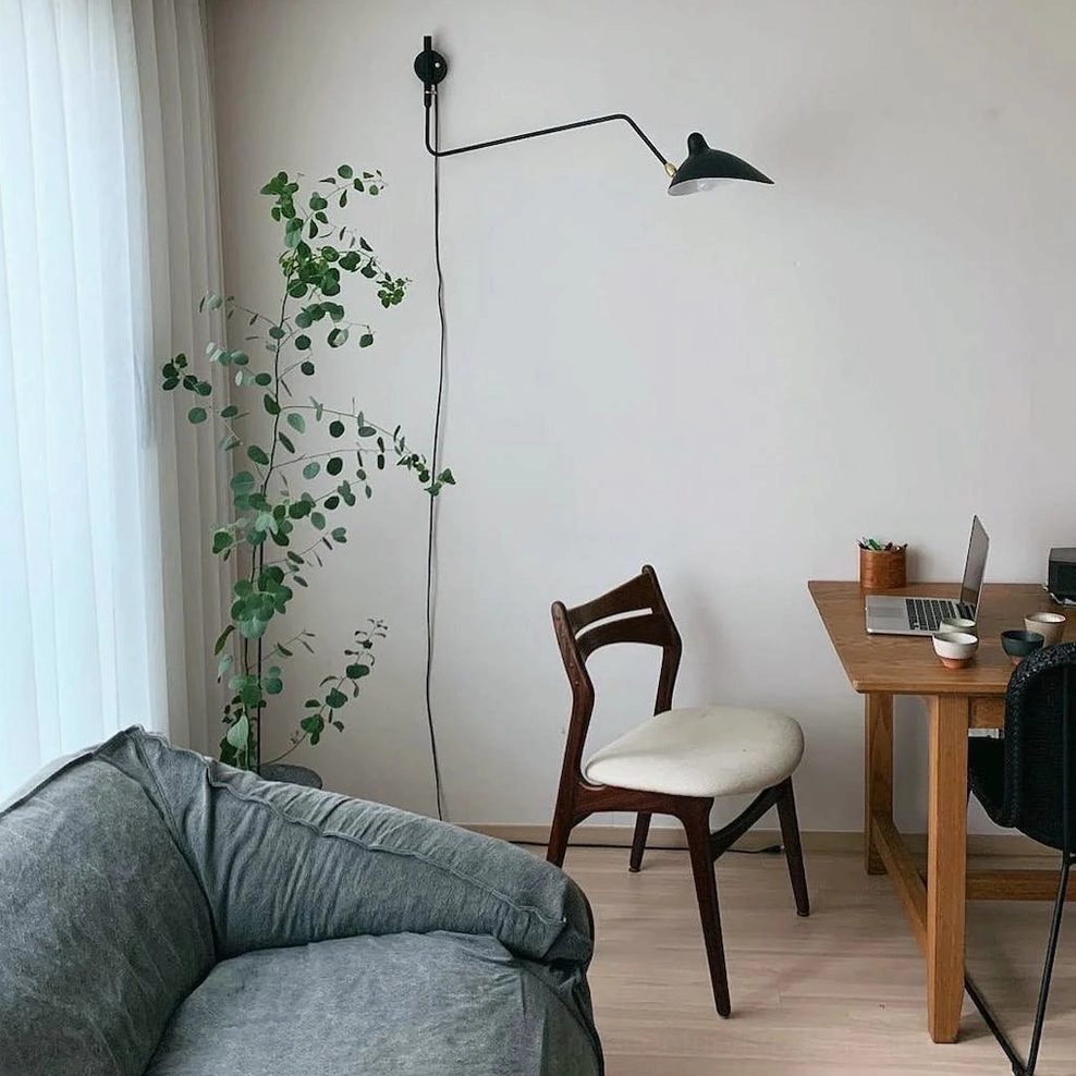 Dual-head plug-in wall lamp with articulating arms in minimalist modern home office setting