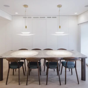 Pair of Hover Disc chandeliers suspended above long luxury dining room table with white shade discs and brass hardware
