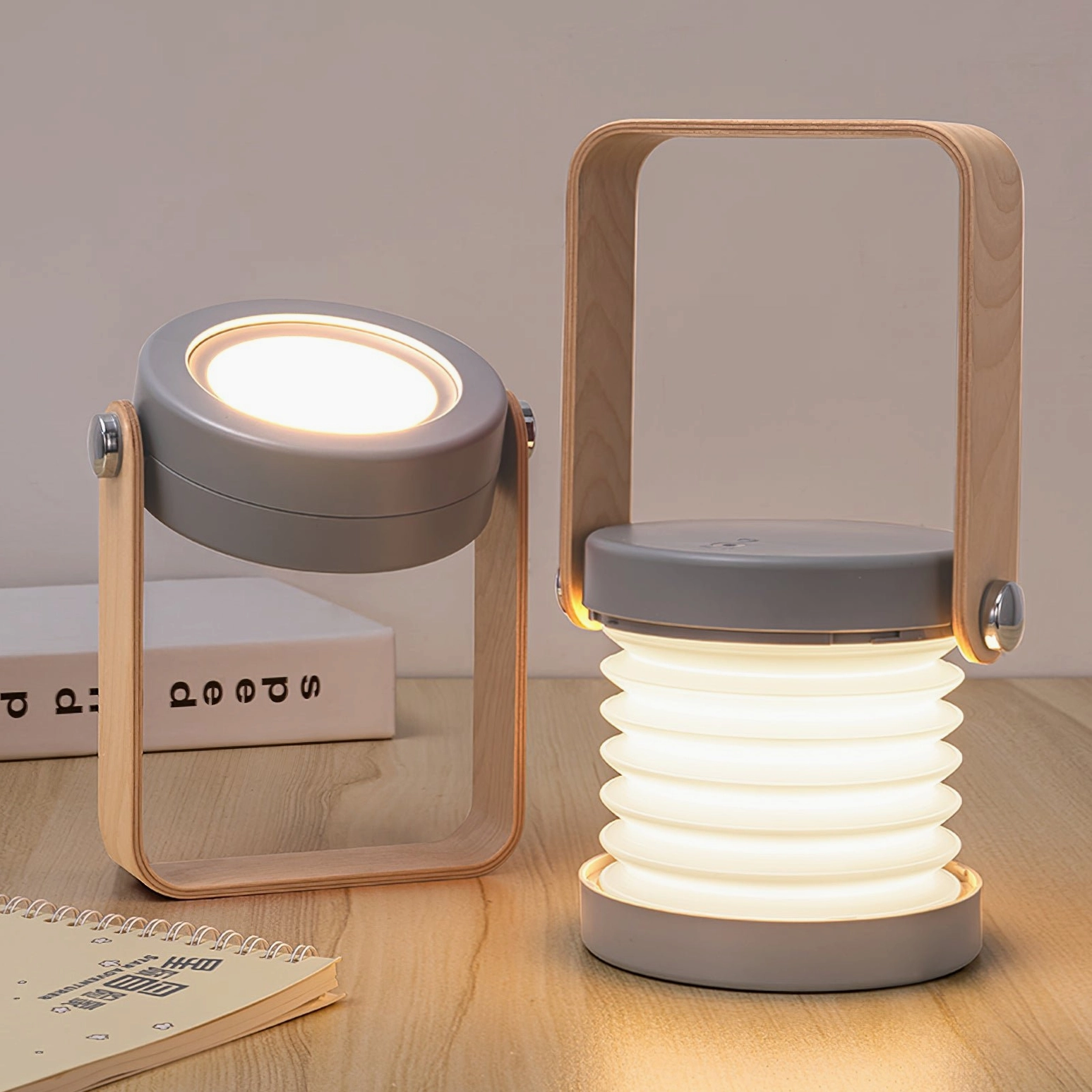 Two lantern table lamps in different finishes on wooden study desk, grey and natural wood color variants showcasing versatile design