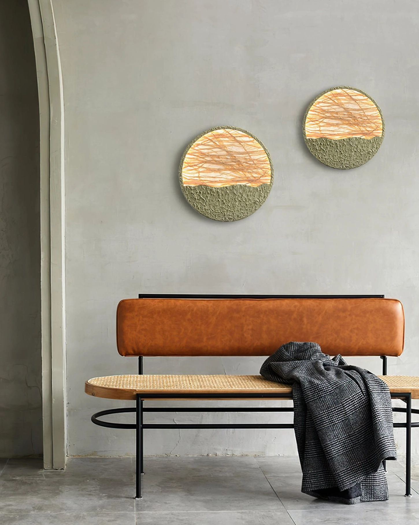 Two natural straw wall lamps installed in entryway seating area with brown leather bench and gray knitted throw blanket