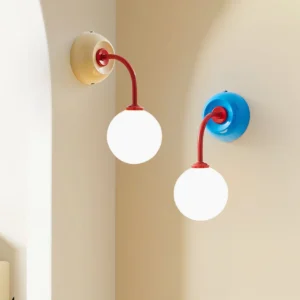 Two Zesta color-block wall sconces installed in warm-toned arched interior, showcasing beige and blue variants with red arms in architectural setting
