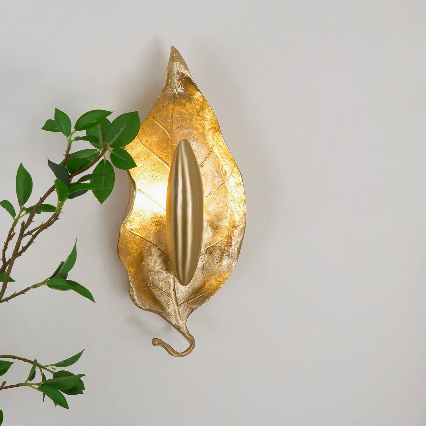 Side profile view of Dumaine brass wall sconce showing curved leaf tail detail and thin stem architecture