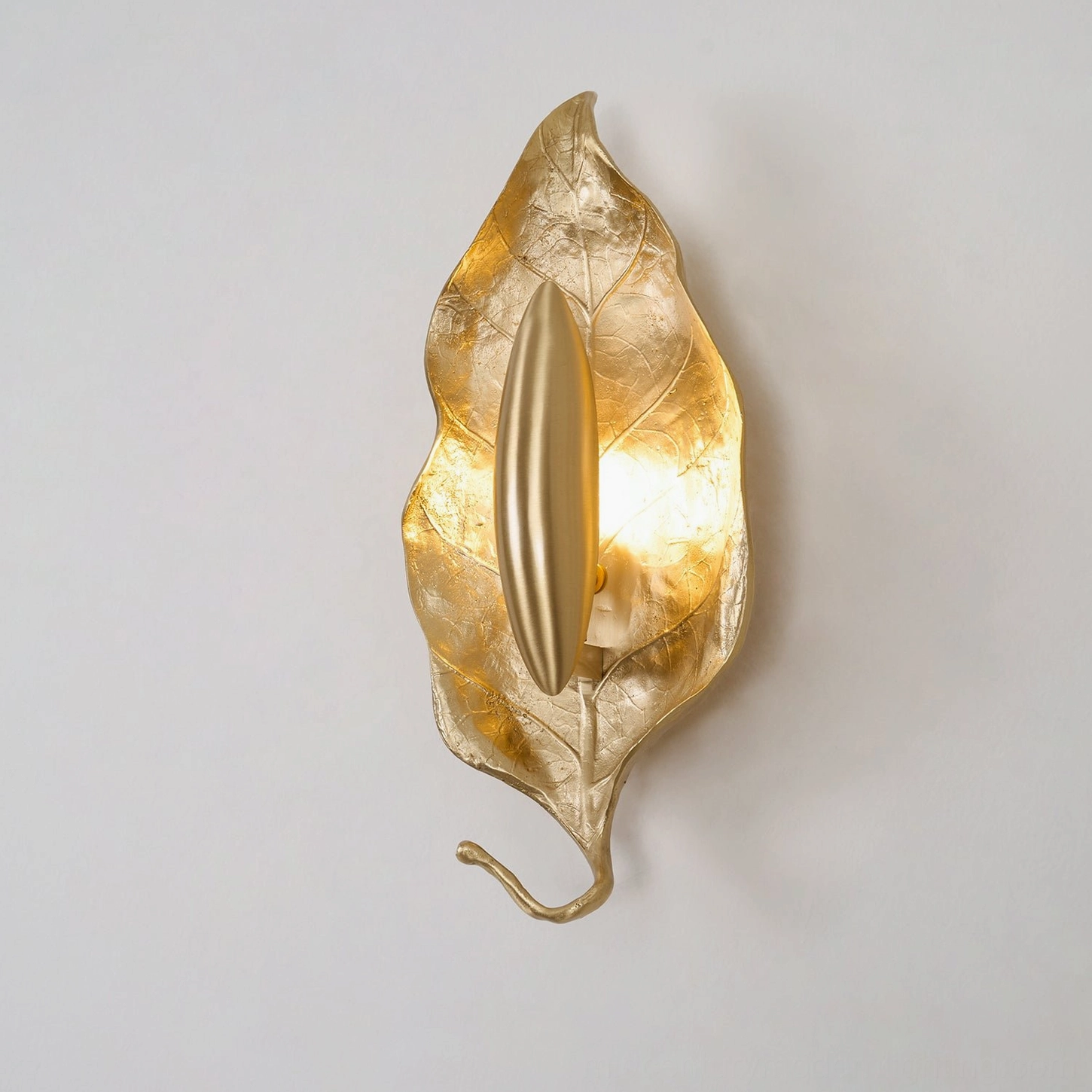 Dumaine brass wall sconce installed showing how warm light creates shadow play on surrounding wall surface
