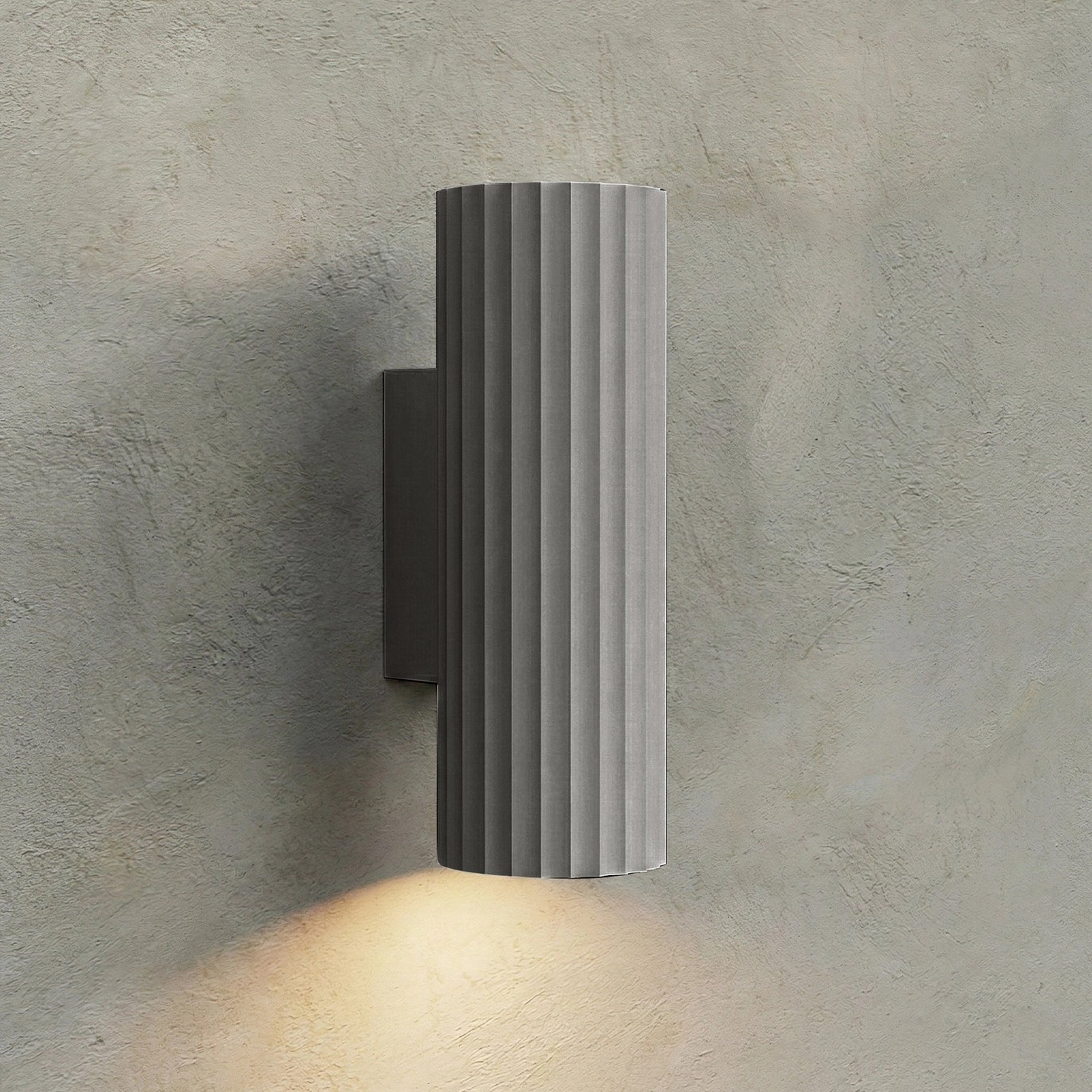 Grey Dunbar ribbed wall sconce with upward and downward light beams on concrete wall, minimalist modern fixture