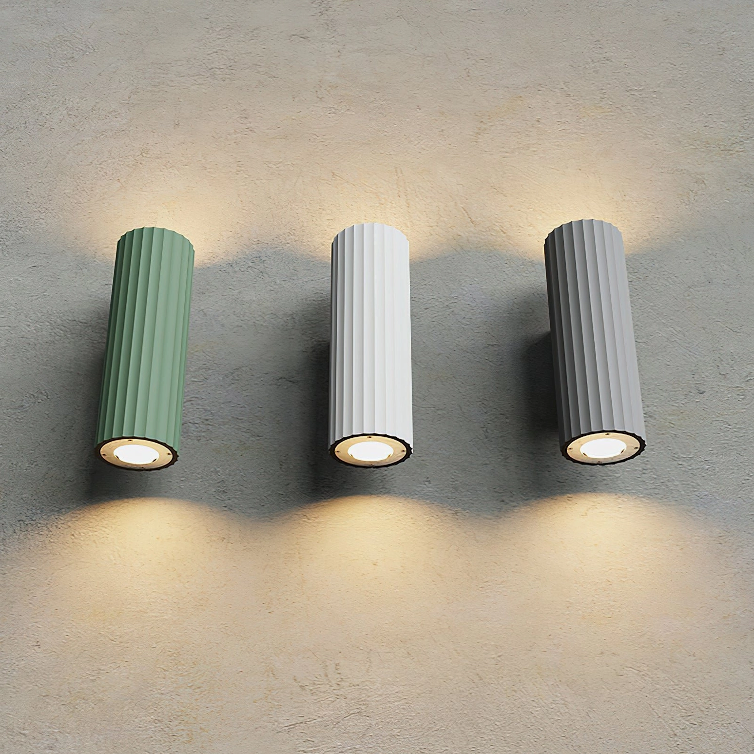 Dunbar wall sconce collection showing three finishes with exposed lamp base and warm dual lighting on concrete