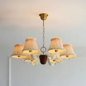 Beige pleated fabric chandelier with brass metal parts and dark wood accents, ceiling level view in minimalist home interior