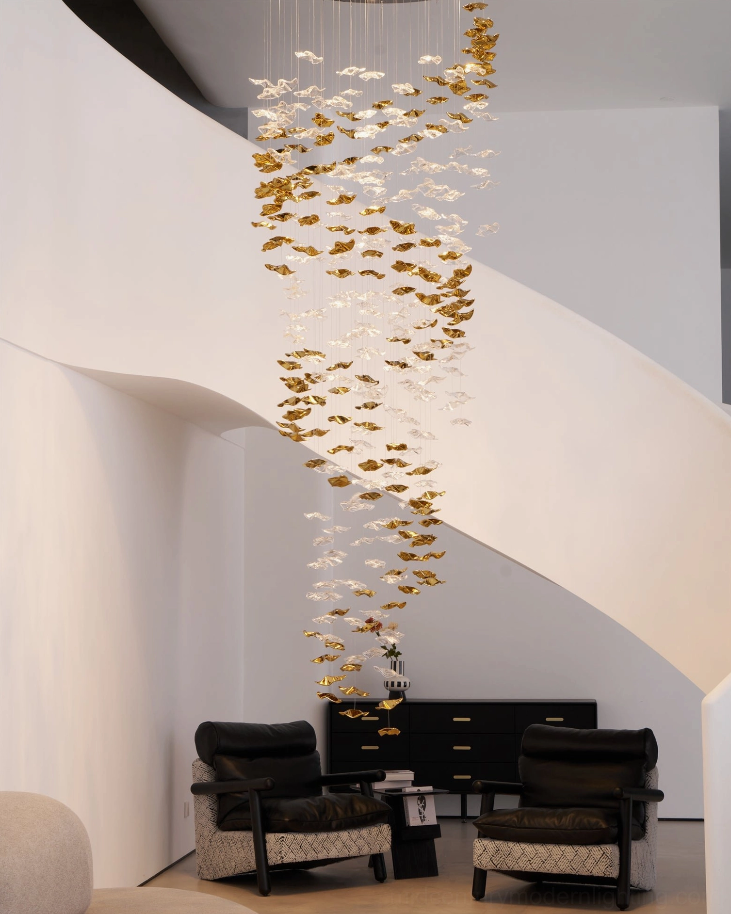 Duplex living room chandelier with gradient golden glass pendants and white staircase architectural backdrop