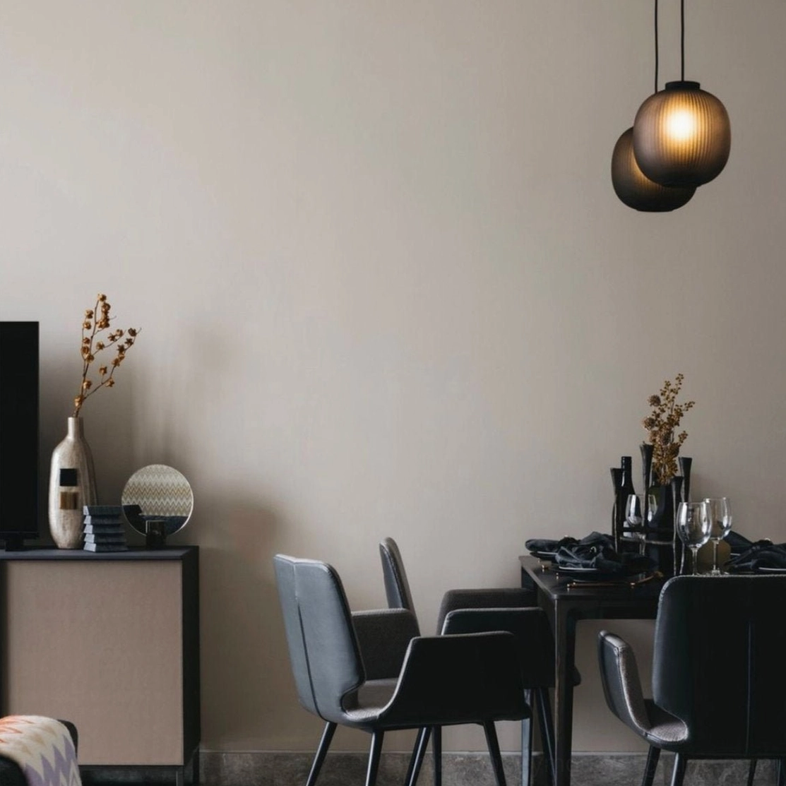 Dark ribbed glass pendant lights in minimalist home dining area with leather chairs
