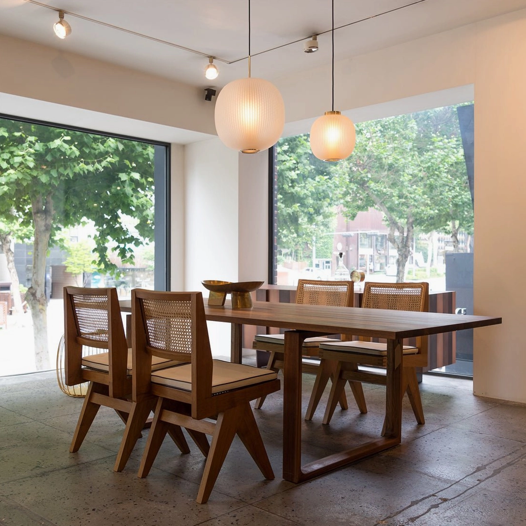 Pair of frosted glass pendant lights hanging in contemporary dining room with natural light