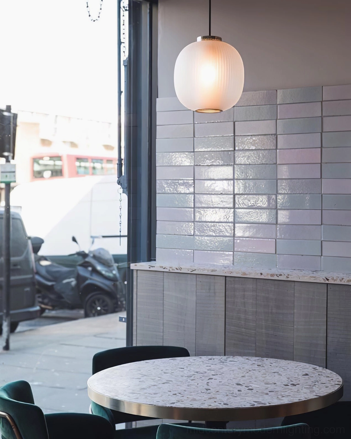 Smooth frosted glass pendant light in street-facing restaurant with terrazzo table