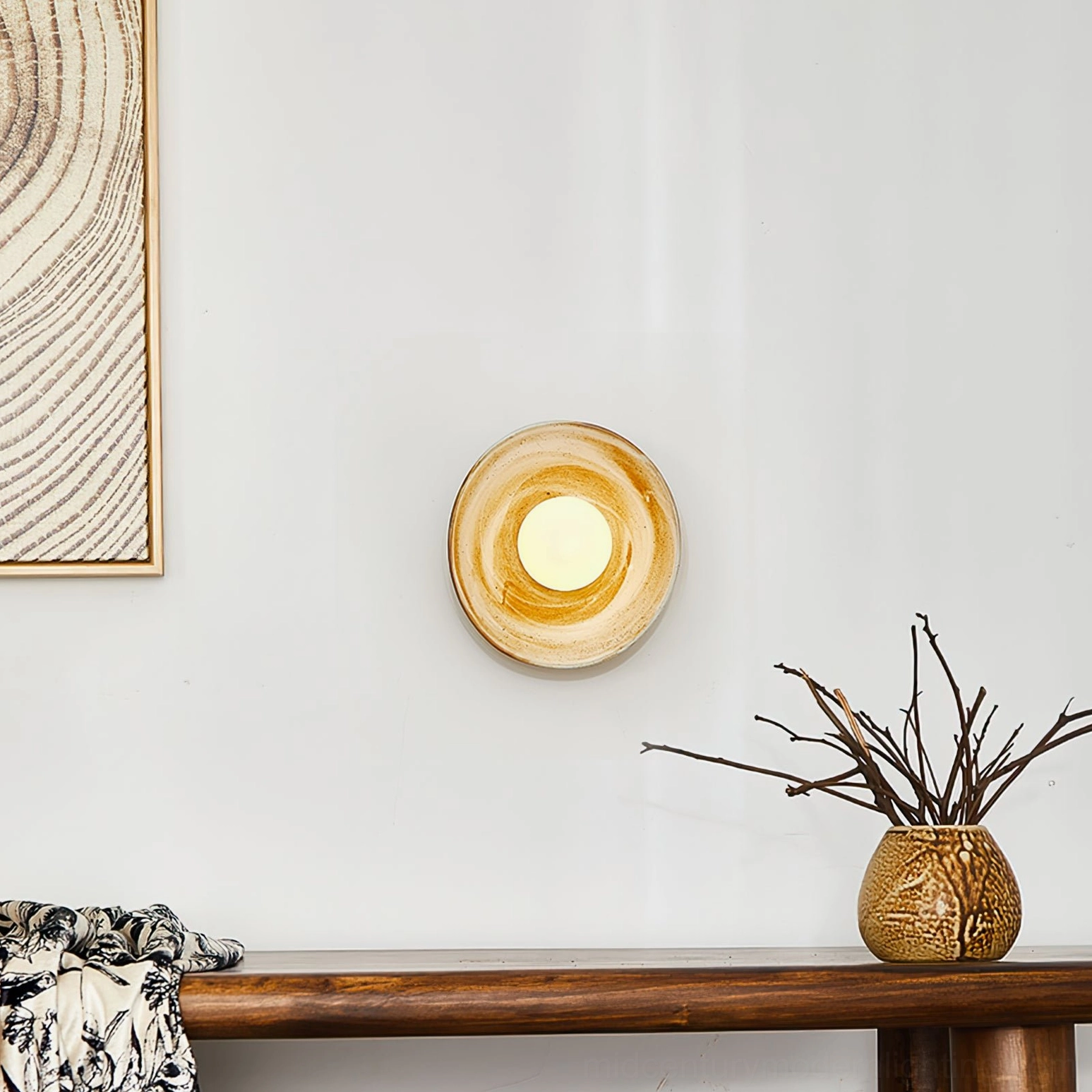 Eala wall lamp frontal view on living space console with marbled ceramic finish and wood wall art