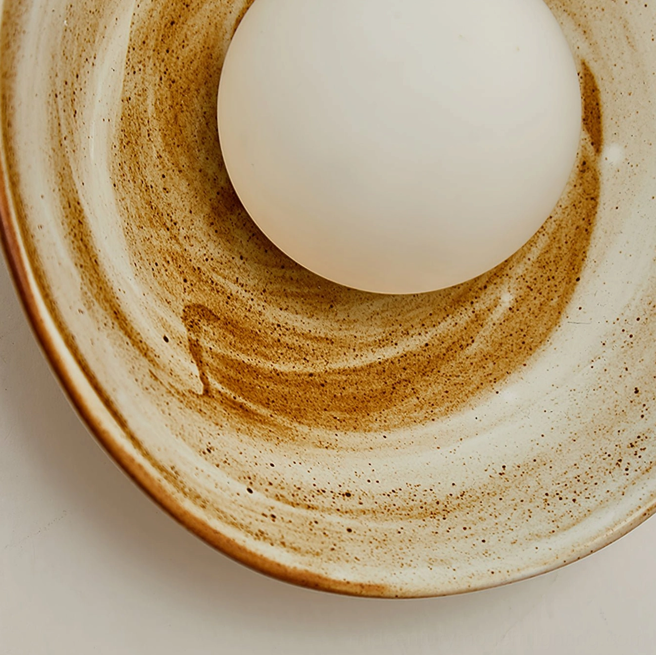 Eala wall lamp unlit close-up showing ceramic bowl structure with marbled brown and white glaze